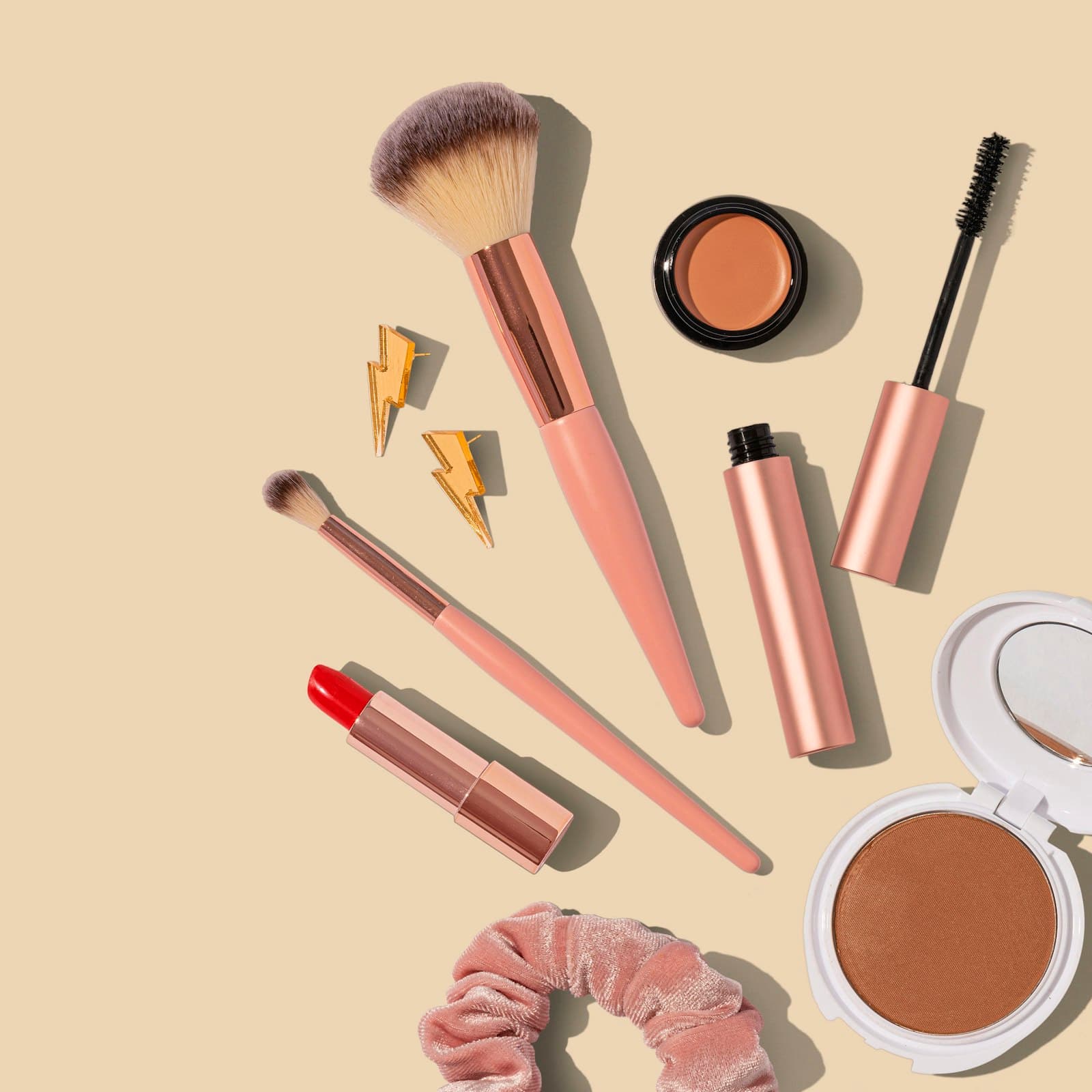 Unbranded makeup flatlay with brushes, lipstick and compact